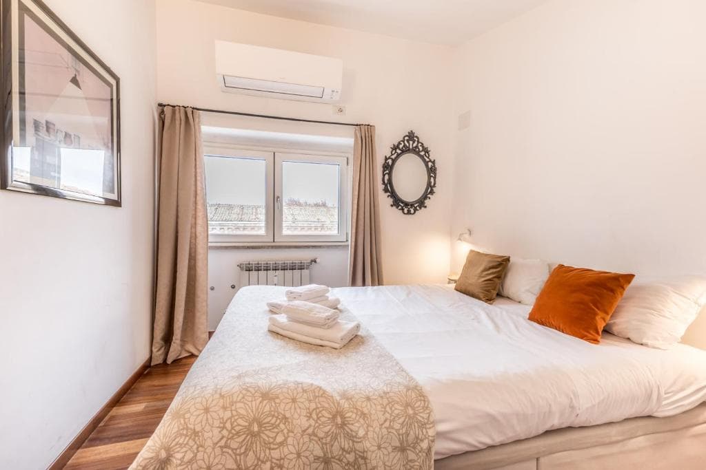 Mezzanine bedroom with double bed and a window onto Rome's rooftops