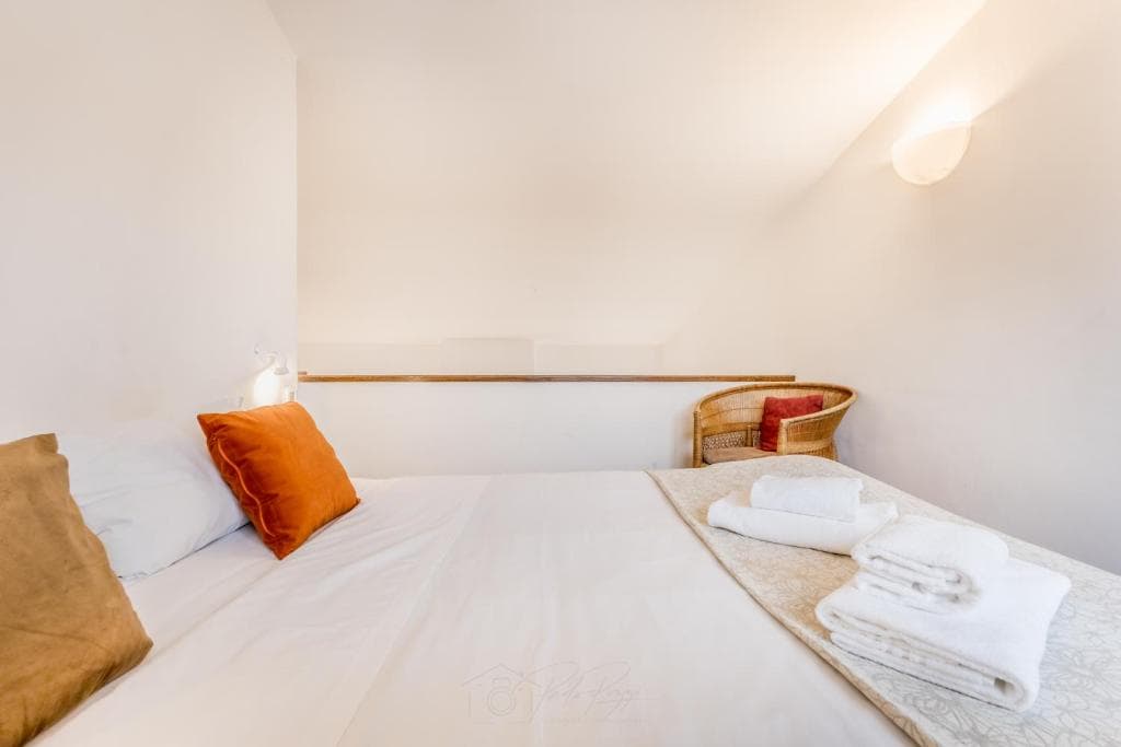 Bedroom on the mezzanine with wicker armchair overlooking the living room