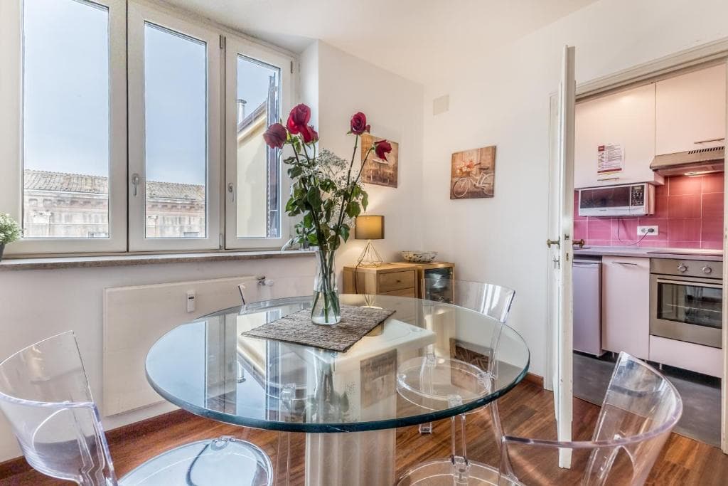 Dining table set with roses, with a glimpse of the kitchen