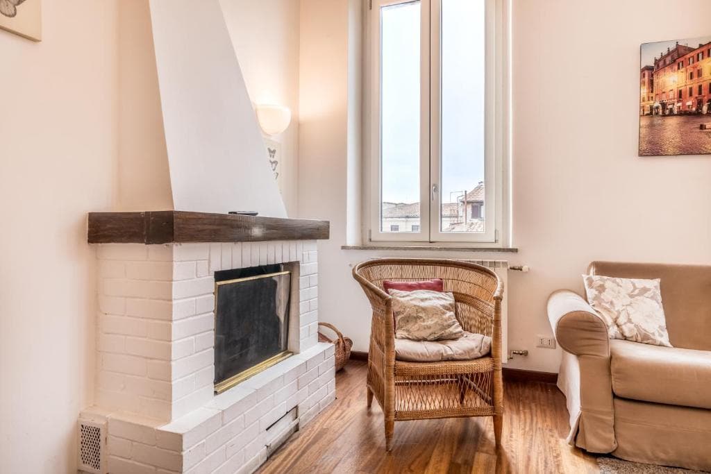 White-brick fireplace with wooden mantel beside a sunlit window