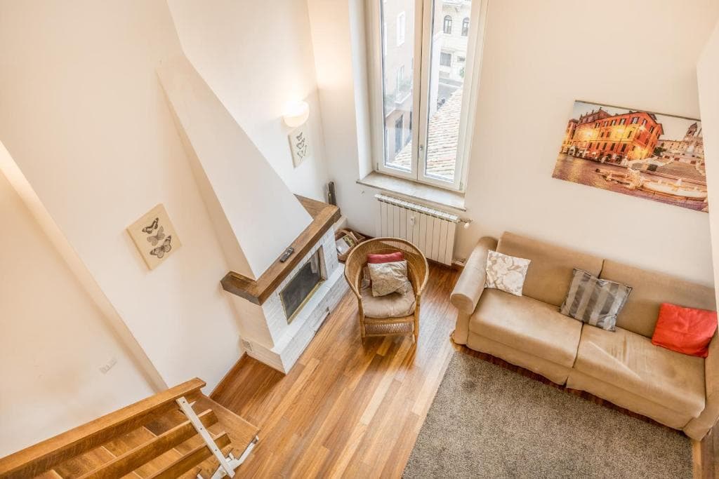 Living room seen from the mezzanine, with fireplace and full-height window