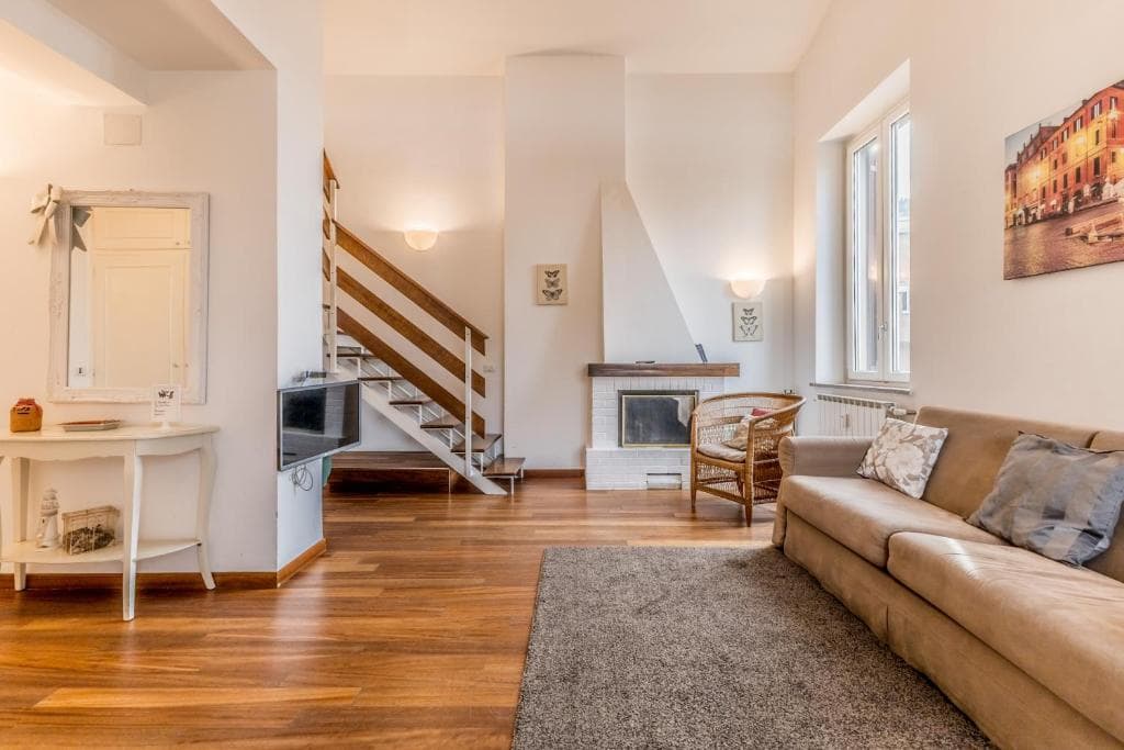 Wide view of the living room with staircase, fireplace and sofa