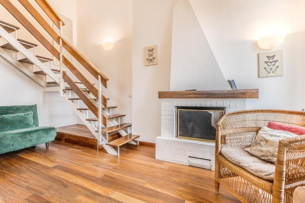 Living room corner with staircase, fireplace and wicker armchair